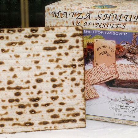 board of matzah leaning on box that says "matza shmura 18 minutes"